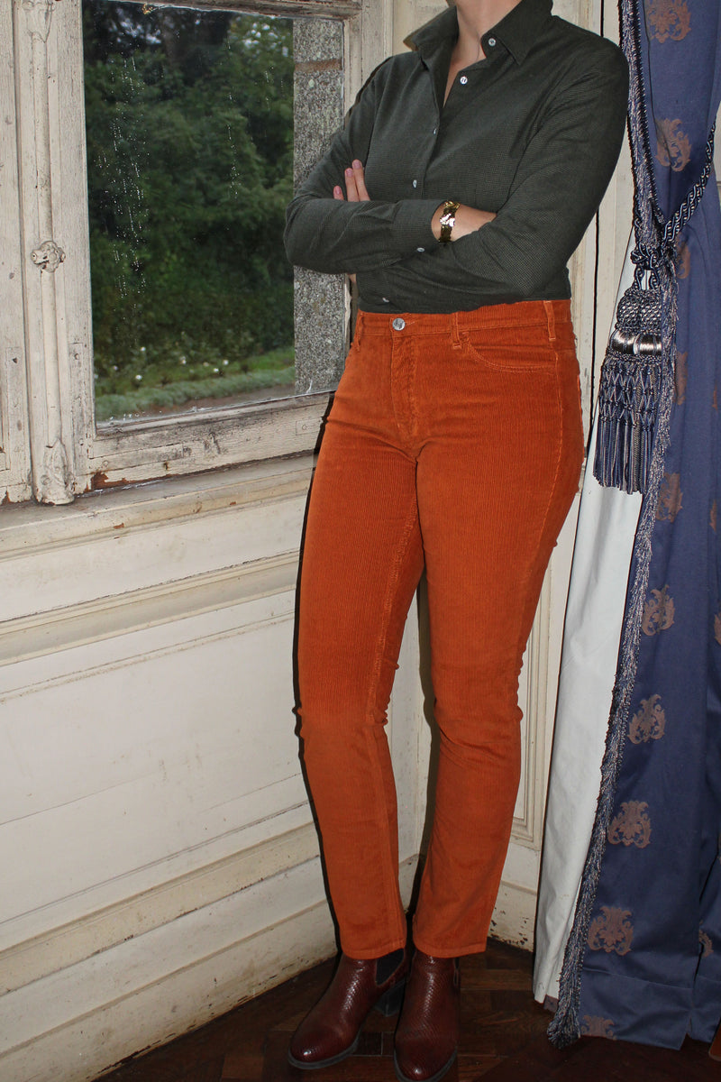 Jeune femme qui porte un pantalon en velours côtelé droit couleur orange rouille