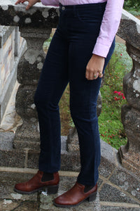 Jeune femme qui porte un pantalon velour côtelé bleu marine taille haute avec une coupe droite confectionnée en Angleterre. 