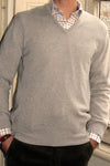 Jeune homme qui porte un pull en cachemire haute gamme beige galet avec un col en V