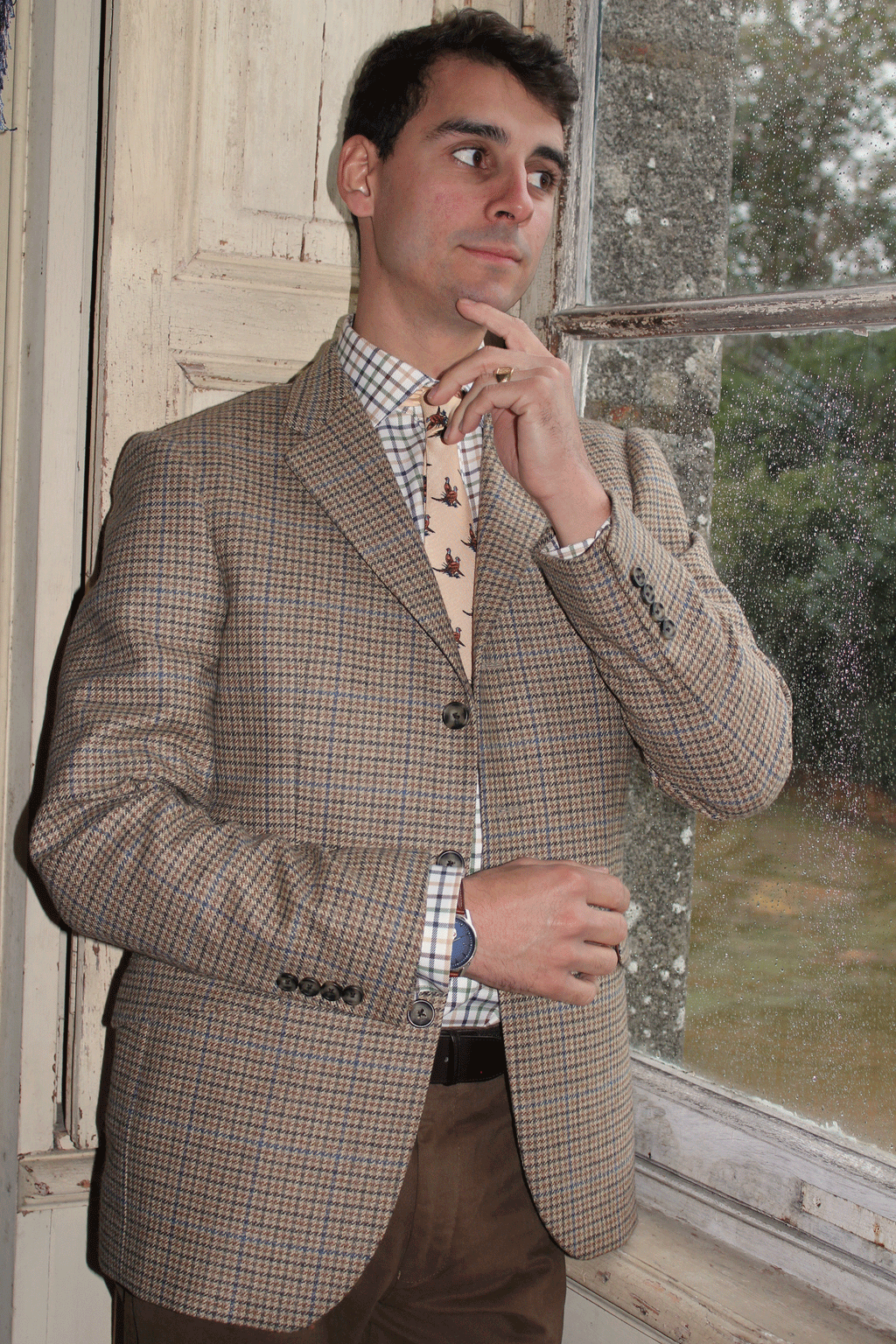 Jeune homme qui porte une veste en Tweed anglais Teviot de couleur marron avec des traits bleu