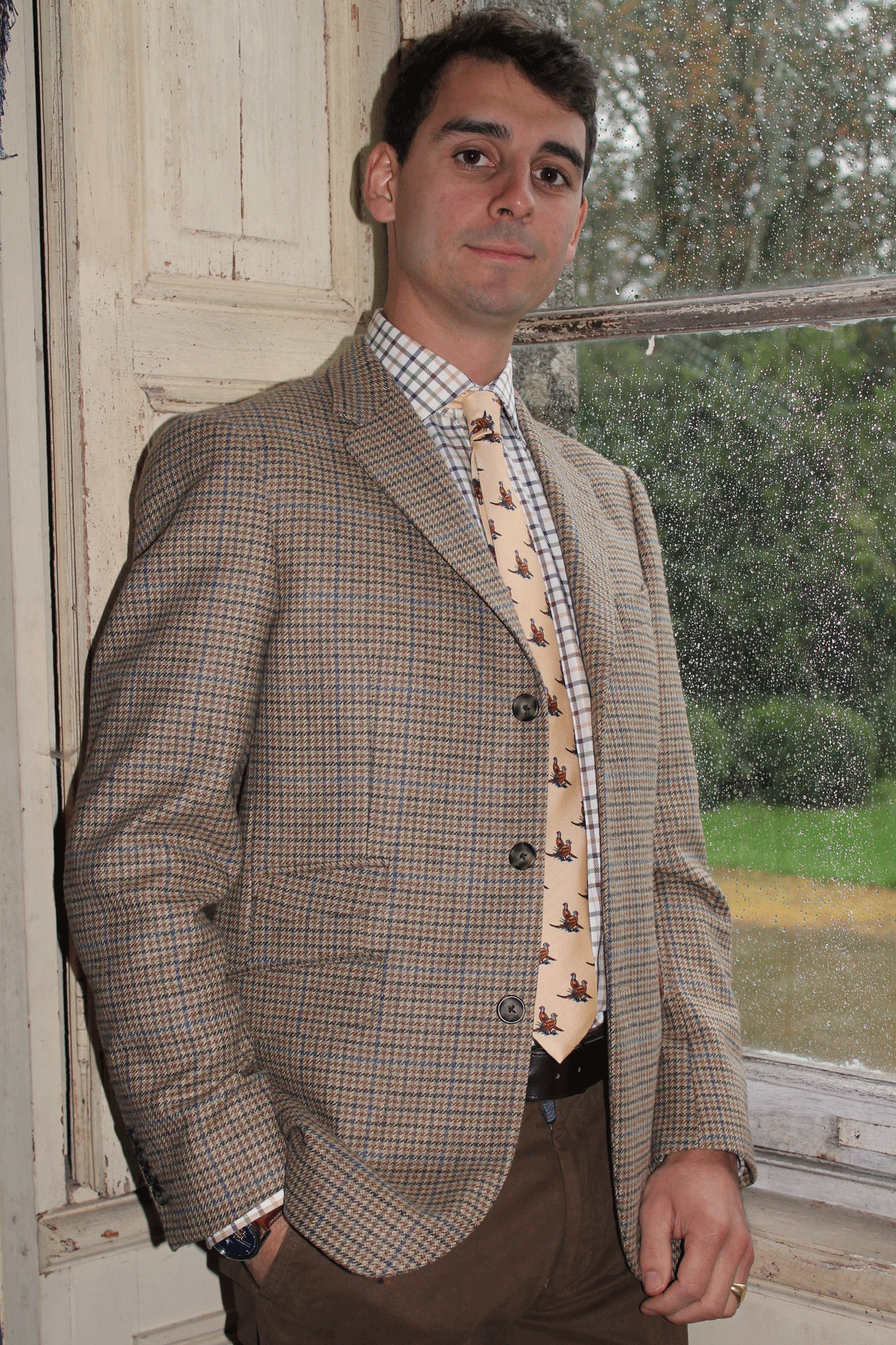 Jeune homme qui porte une veste en Tweed anglais Teviot de couleur marron avec des traits bleu